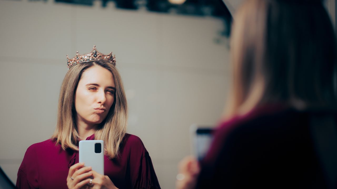 Frau mit Krone und Smartphone.